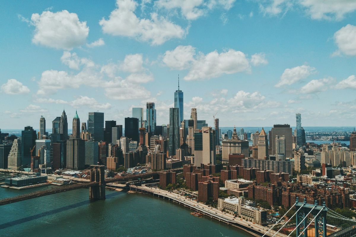 The Manhattan skyline and Brooklyn Bridge under a blue sky